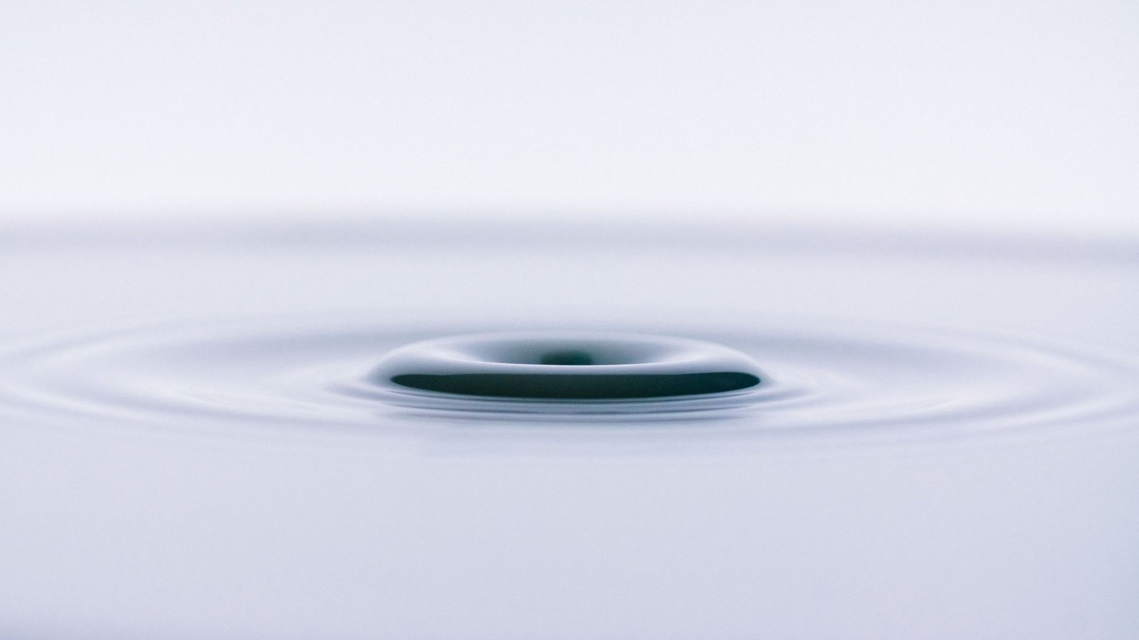 A single drop landing on still water, sending out rings.