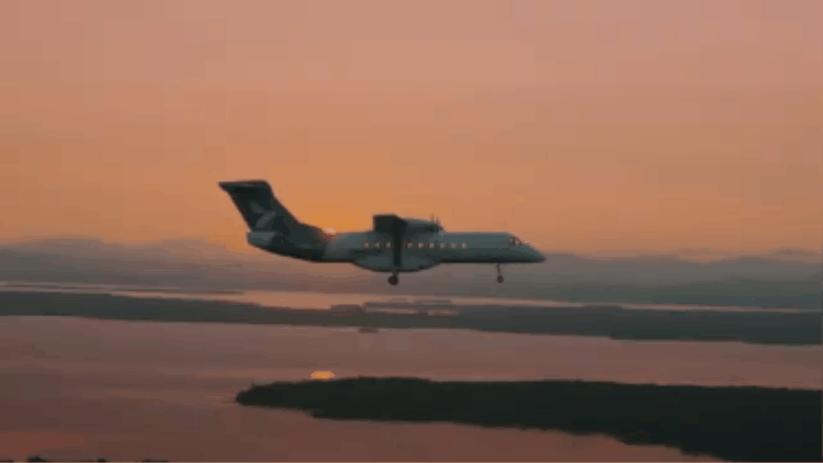 Animated clip of a twin-engine airplane flying low over water at sunset.